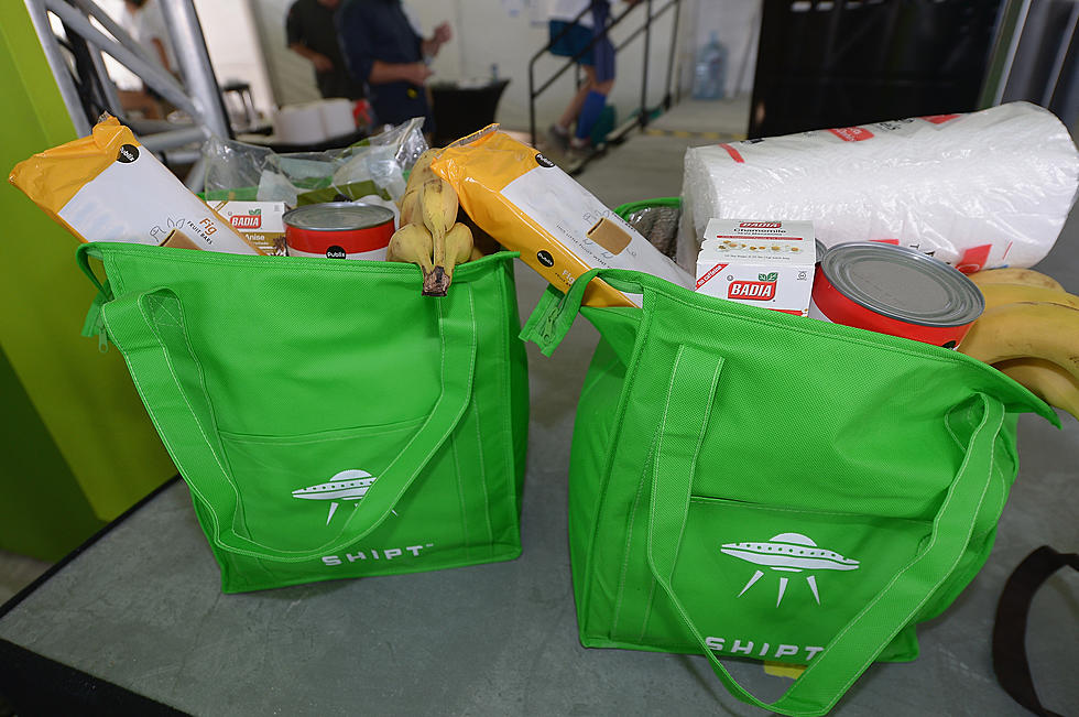 Two bright green reusable shopping bags filled with groceries. The text on the shopping bags reads "Shipt" in white letters.