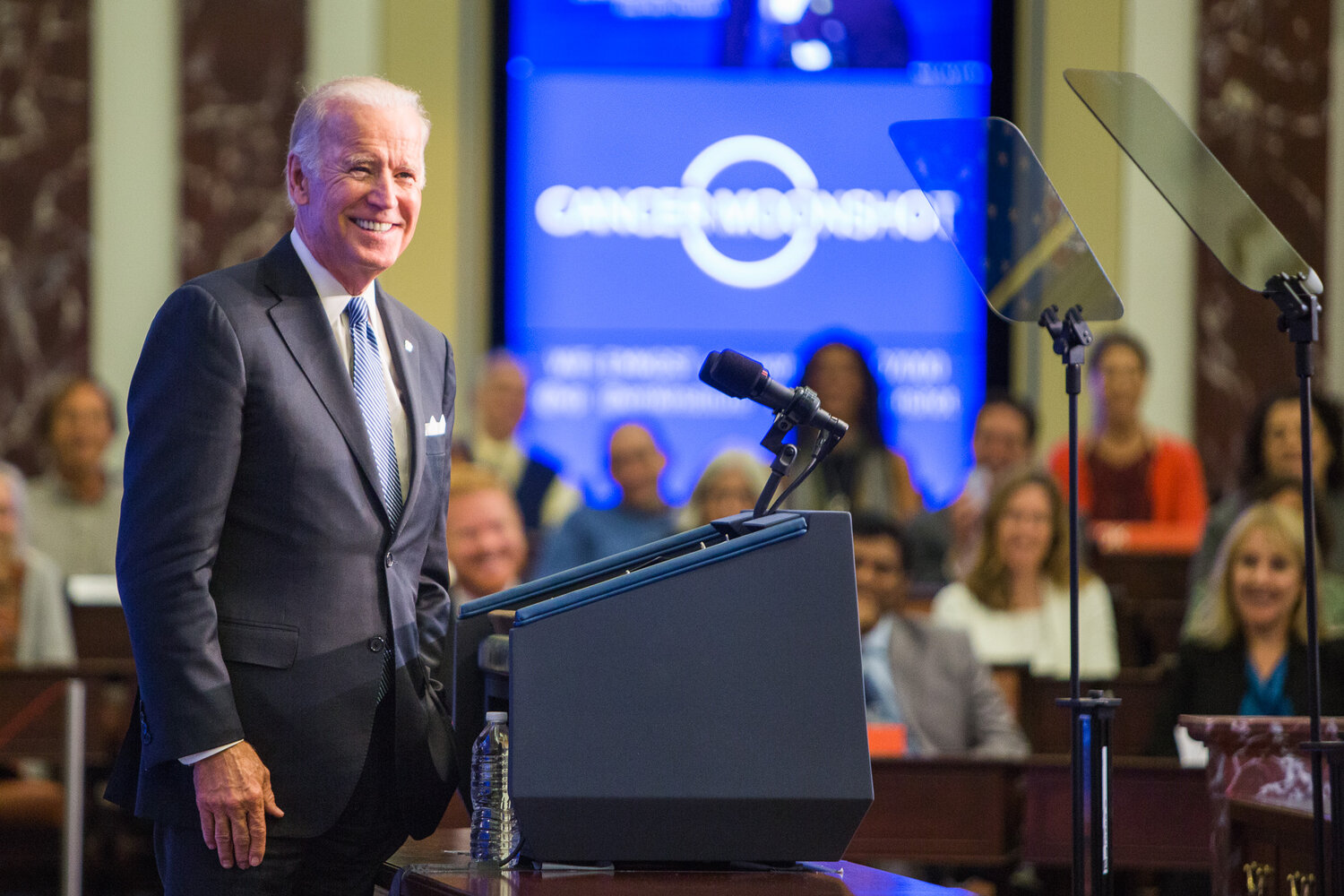 Joe Biden smiles at a crowd as he stands at a podium.