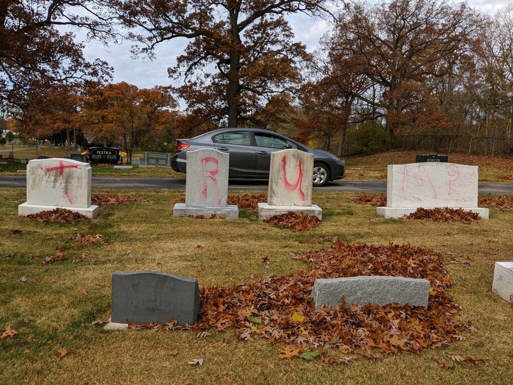 Four gravestones, with T-R-U-MP spraypainted on them in red.