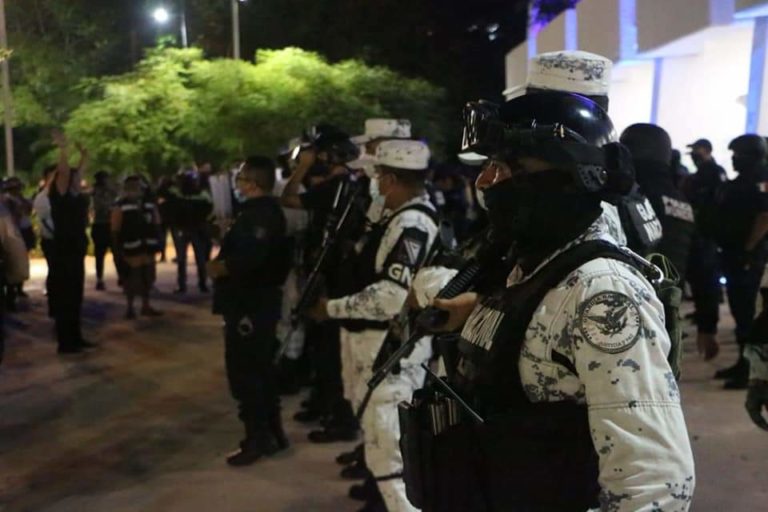 Police officers in Mexico stand heavily armed in Cancún