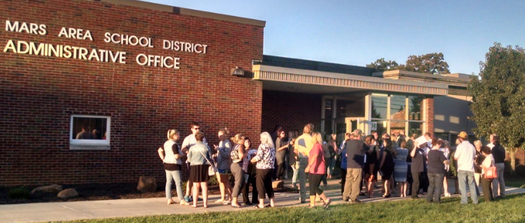 Group of people congregate outside the Mars Area School Administrative Office.