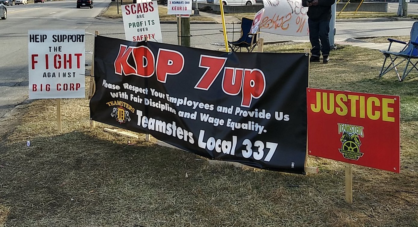 The photo shows signs supporting the Teamsters struggle, on a main road near the bottling plant.