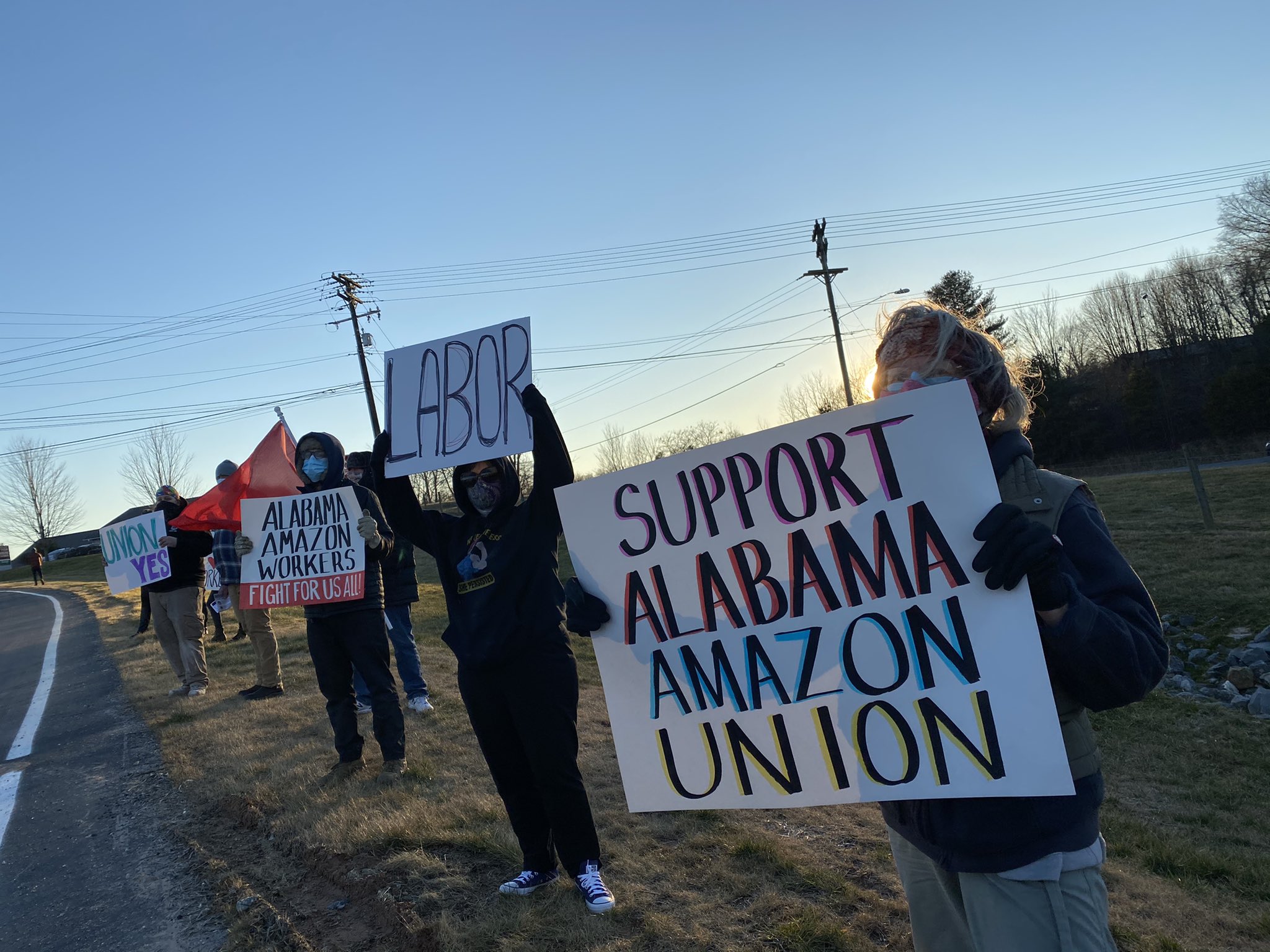 The photo shows people holding signs in support of Alabama Amazon workers.