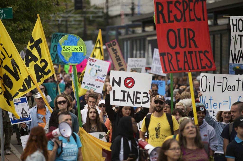 Protesters in Minnesota march and hold signs in protest of the Line 3 pipeline.