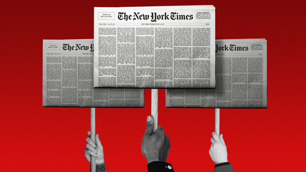 Three hands hold up picket signs that have the New York Times front page on them.