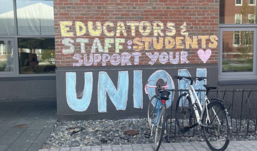 A brick wall, on which someone has written in colorful chalk, "Educators & Staff: Students Support Your Union!"
