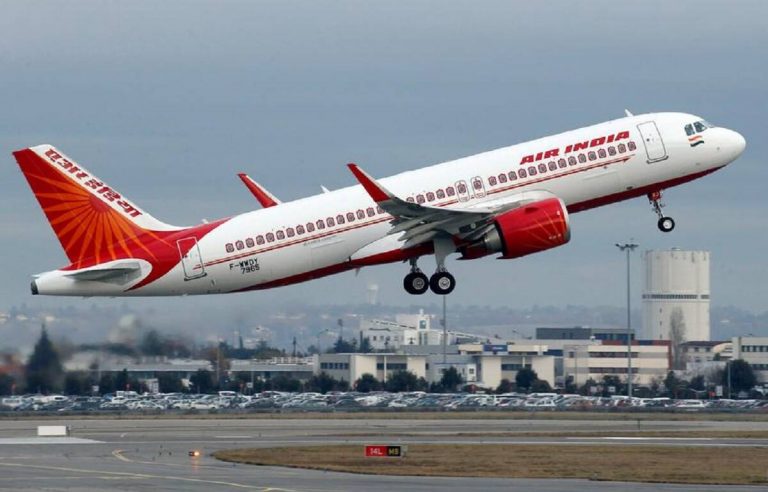 A white and red Air India plane takes off.