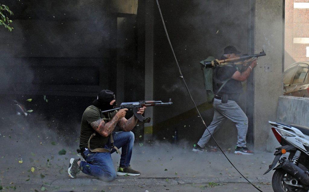 Two men kneel with machine guns and face to the right during clashes in Beirut on October 14.