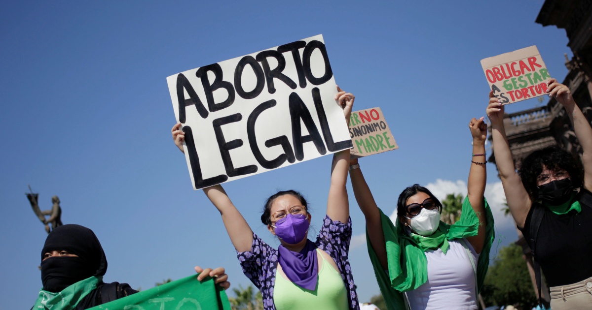 Chilean women wear grean and hold up signs at an abortion rally. The sign reads "Aborto legal" or "Legalize abortion"