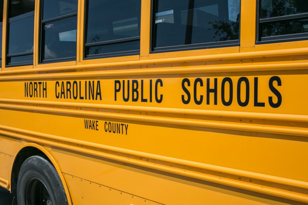 The side of a yellow-orange school bus that reads "North Carolina Public Schools" and "Wake County"