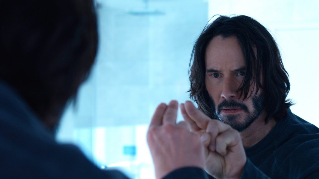 Keanu Reeves as Neo poking his finger into a mirror.