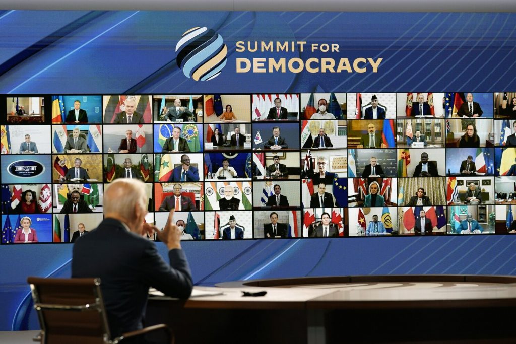 Biden at the Democracy Summit on December 9. He's in a chair facing a screen with all the attendees.