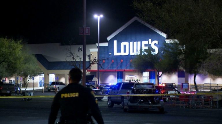 A police officer approaches police tape around a Lowe's