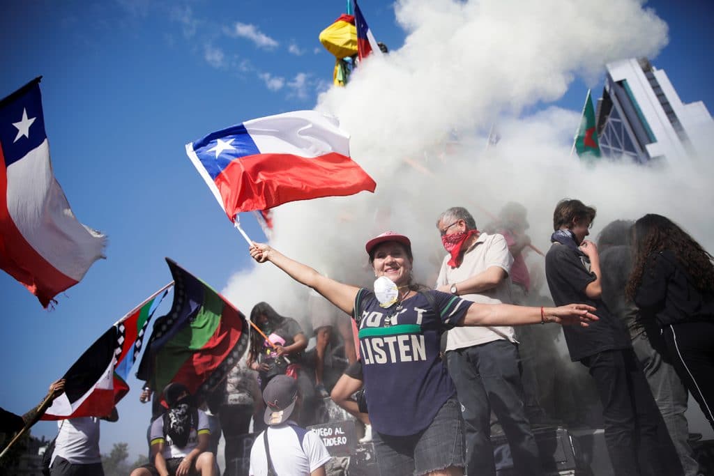 Woman waves chilean flag in front of smoke