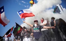 Woman waves chilean flag in front of smoke