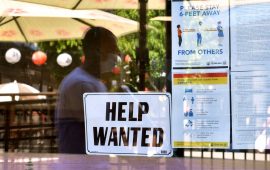 A 'Help Wanted' sign is posted beside Coronavirus safety guidelines in front of a restaurant in Los Angeles, California