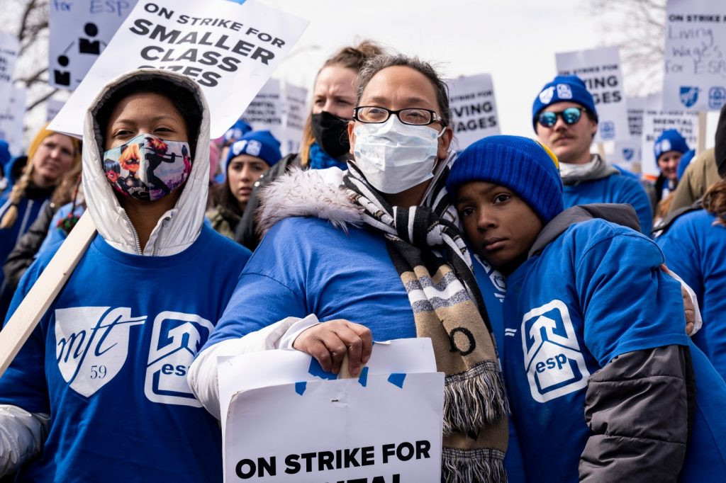 Minnesota teachers union on strike outside, holding signs and wearing blue shirts.