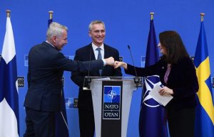 NATO Secretary-General Jens Stoltenberg looks on as Finnish Foreign Minister Pekka Haavisto (left) and Swedish Foreign Minister Ann Linde (right) bump fists after holding a joint press conference after their meeting at NATO headquarters in Brussels on Jan. 24