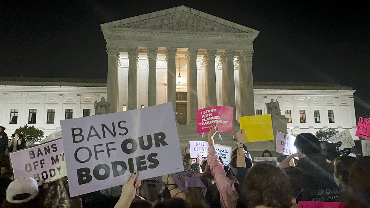 A crowd of people gathered outside the Supreme Court in Washington. A draft opinion circulated among Supreme Court holding signs that read bans off our bodies.