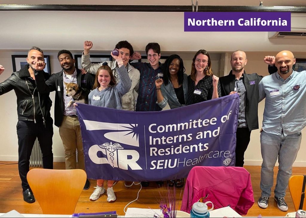 Resident physicians hold a purple banner that reads "Committee of Interns and Residents SEIU"