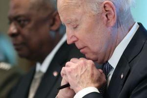 Joe Biden looking downward with his eyes closed. His hands are clasped, as if praying, although he's probably just thinking.