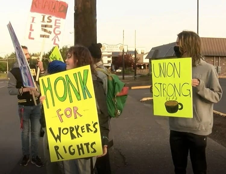 Eugene, Oregon Starbucks workers on strike hold signs outside the store that read "HONK for Workers Rights."