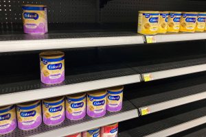Semi-empty store shelf with a few cans of baby formula.