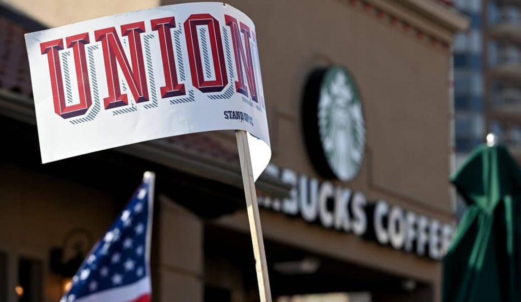 A protester waves a sign that read "unionize" near the Country Club Plaza Starbucks store where dozens of Starbucks employees and union supporters protested alleged anti-union tactics by the company Thursday, March 3, 2022.