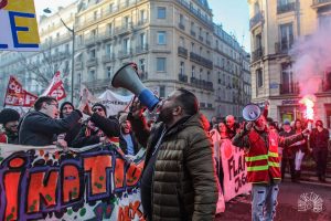 French Trotskyist worker Anasse Kazib holds a megaphone and speaks to a crowd at a protest