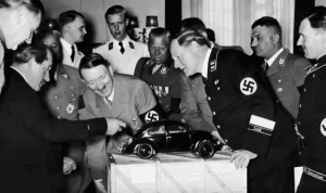Adolf Hitler admires a model of the Volkswagen car. He is with the designer Ferdinand Porsche, left, and various Nazi officials.