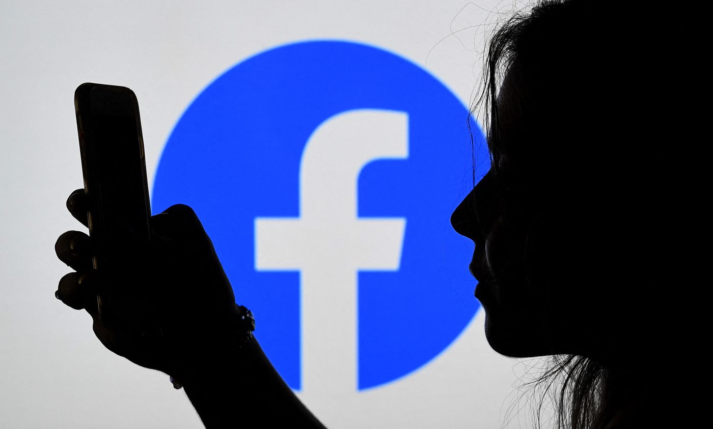 A silhouette of a person with long hair holding a phone. In the center of the image in the background is a blue circle with the Facebook logo in the center.