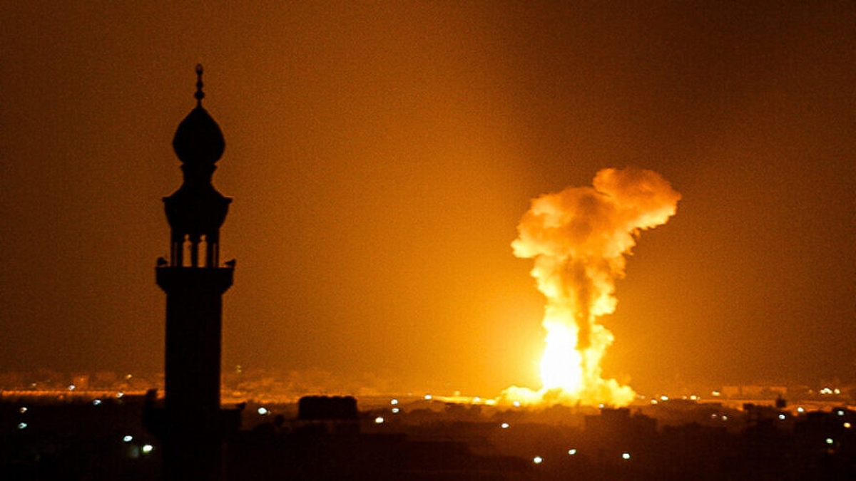 An explosion lihghts up the night sky in front of a mosque in Gaza