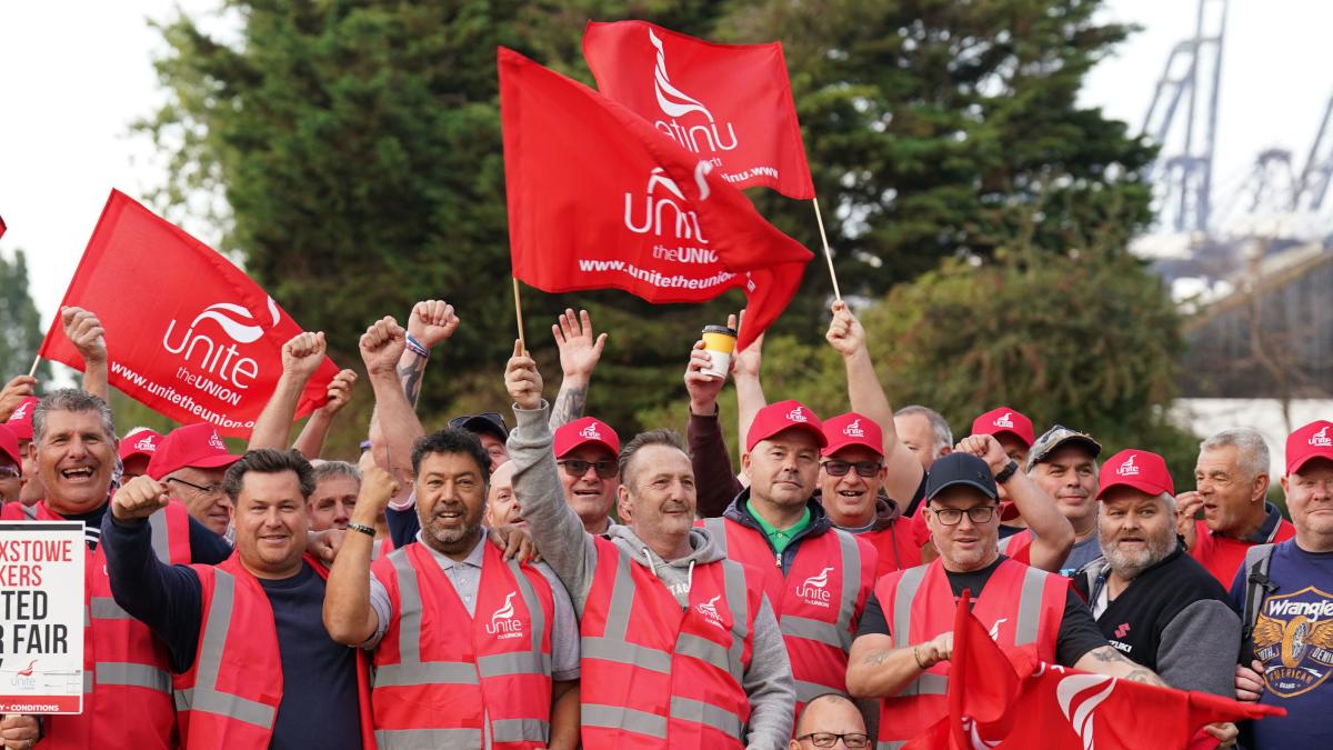 Striking port workers at Felixstowe wear red vests and hold flags for Unite union.