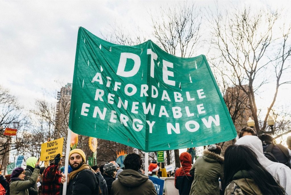 Detroit protesters hold green banner that says "DTE" Affordable Renewable Energy Now