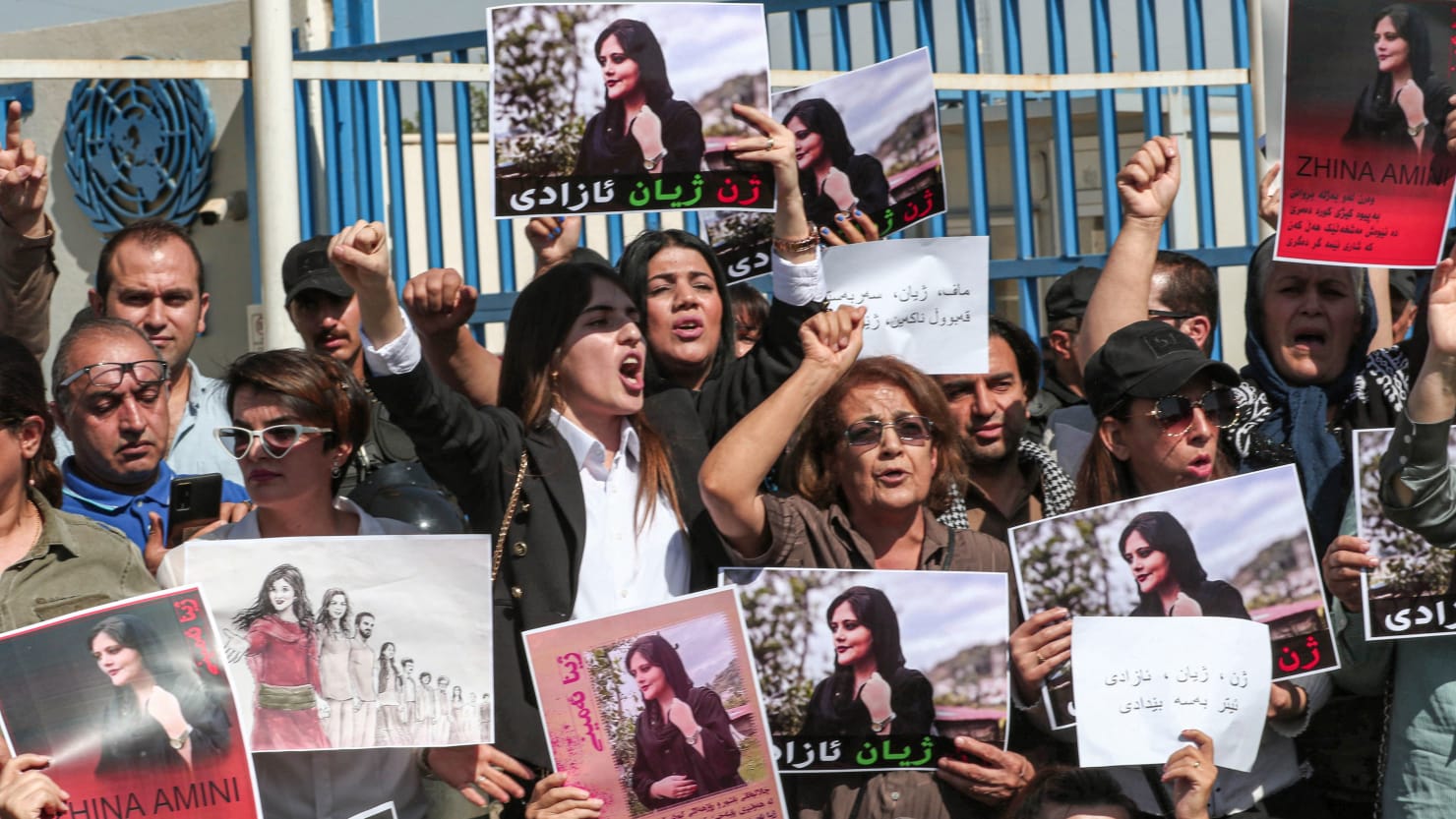 Iranian women and some men protest while holding images of a woman who was killed in police custody.