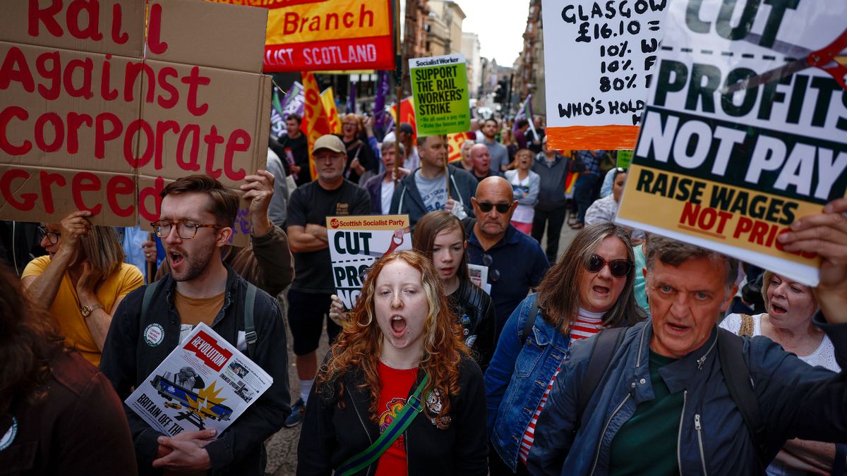 UK workers protest in favor of rail strikes, holding placards.