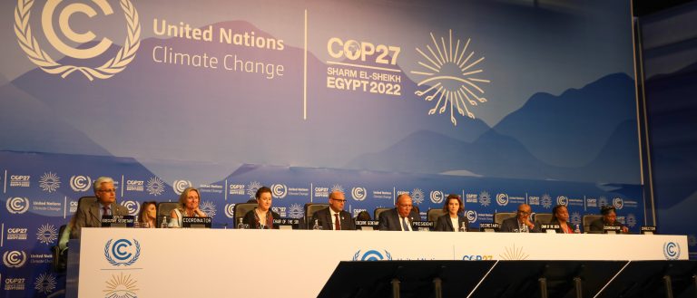 Government representatives sit at a long table in front of a COP27 banner.