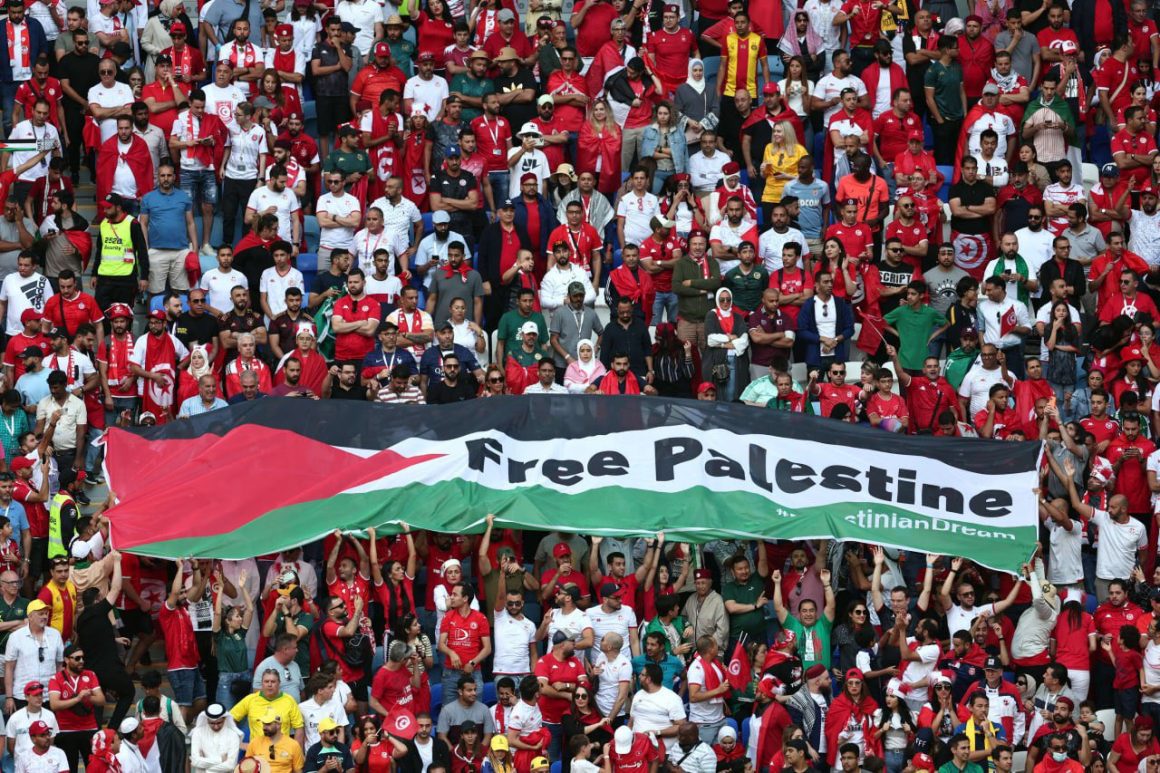 The crowd at the 2022 FIFA World Cup, holding a huge Palestine flag that reads "Free Palestine"