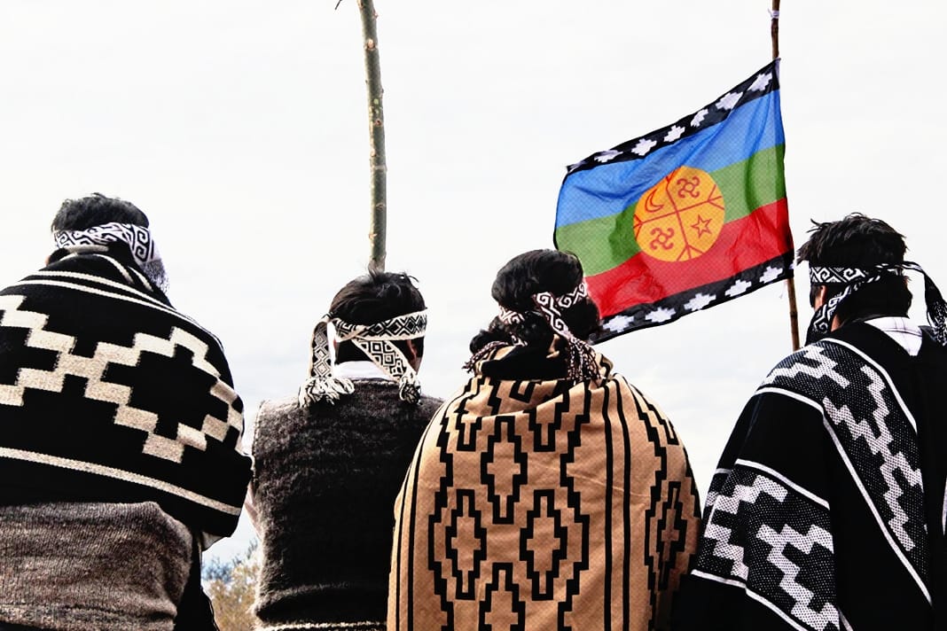 Mapuche people standing with a flag