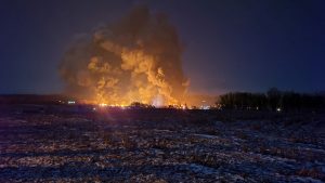 East Palestine, Ohio in the distance at night, smoke and fire springing up due to the train derailment.
