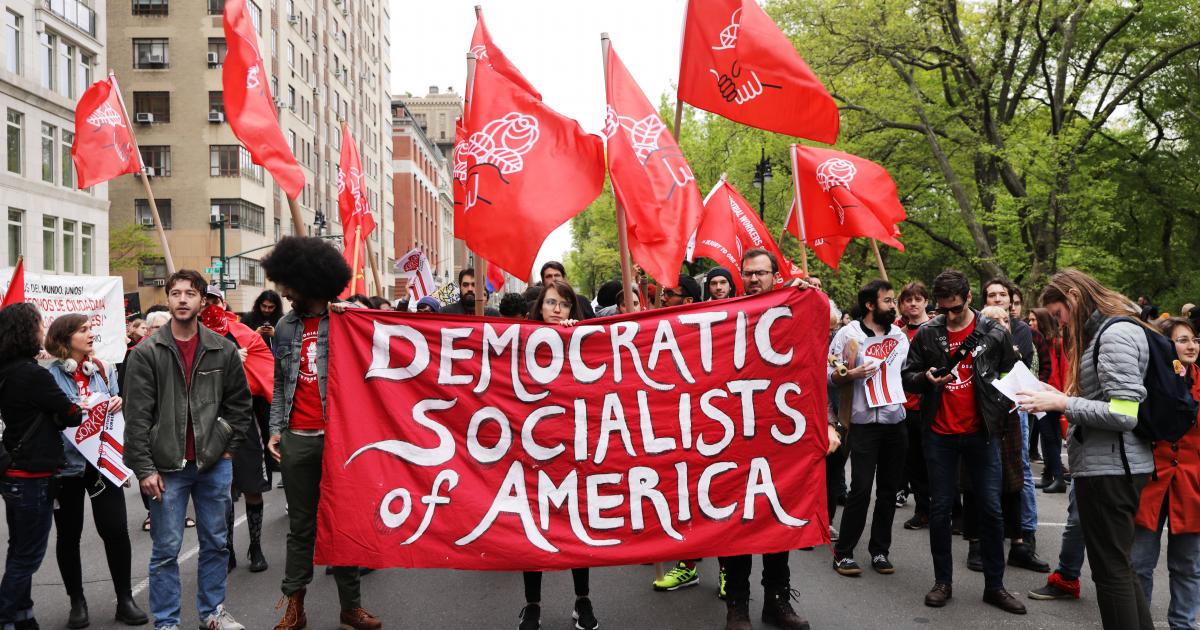 DSA members at a protest hold a red banner.