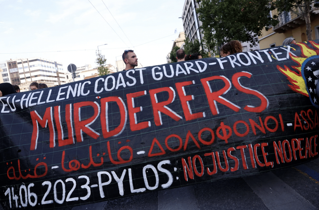 Protesters in Athens against the shipwreck carry a sign reading "Hellenic coast guard-Frontex murderers"