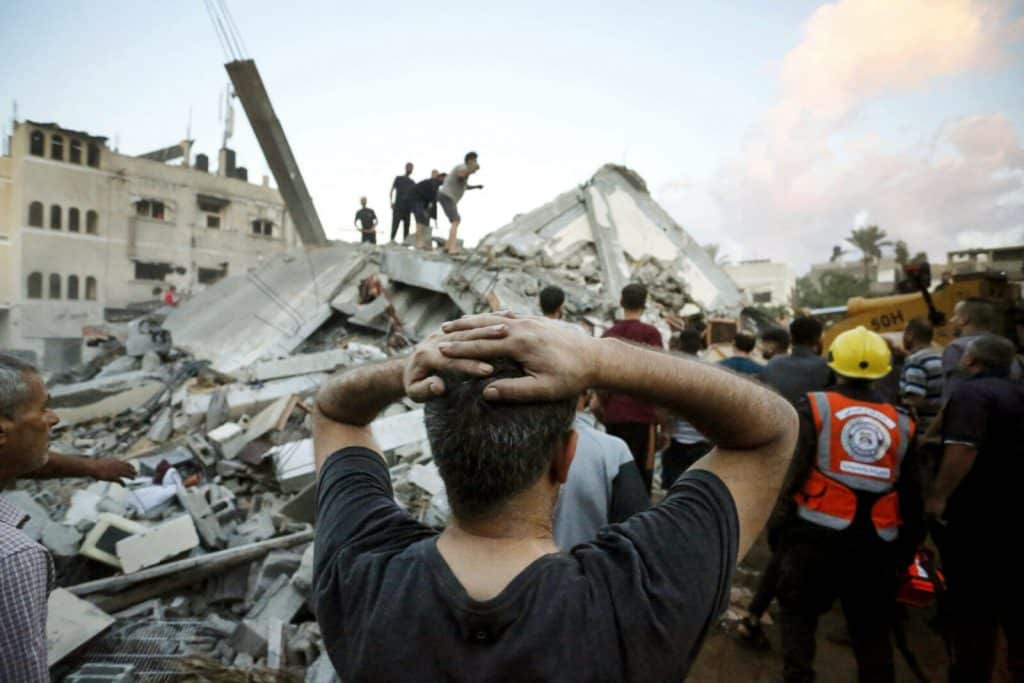 EDITORS NOTE: Graphic content / TOPSHOT - A man reacts as he watches recuers and civilians remove the rubble of a home destroyed following an Israeli attack on the town of Deir Al-Balah, in the central Gaza Strip, on October 15, 2023, amid the ongoing battles between Israel and the Palestinian Islamist group Hamas. Thousands of Palestinians have gathered in the south of the Gaza Strip, laying out beds on the streets after UN-run schools filled up following Israel's warning to evacuate the north of the impoverished enclave.