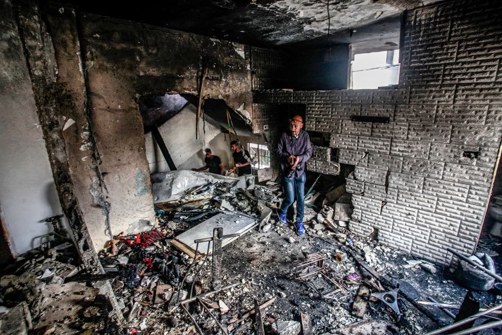 A man stands in the wreckage of a home in the West Bank.