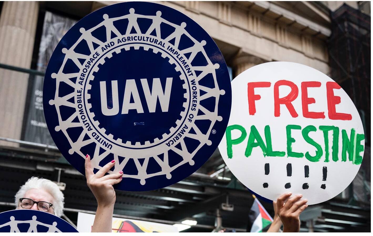 A UAW sign is held next to a "Free Palestine" sign