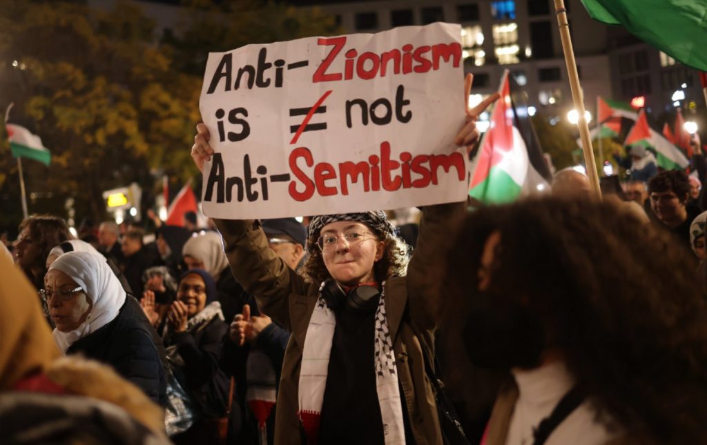 A protester holds up a sign that reads "Anti zionism is not anti-semitism"