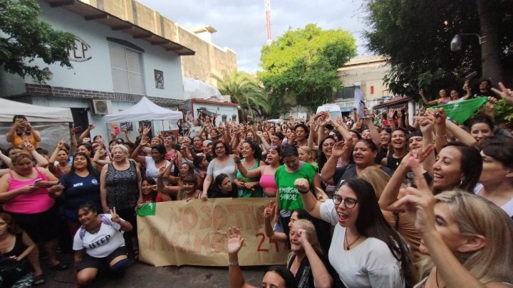 A group of Argentine women gather and hold their fists up in solidarity