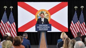 Florida governor Ron DeSantis stands at a podium that reds "Higher Education Reform"
