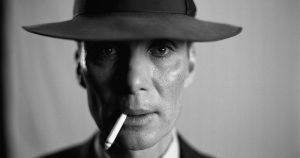 Cillian Murphy as Robert Oppenheimer stares into the camera with a hat pulled over his eyes and a cigarette hanging out of his mouth