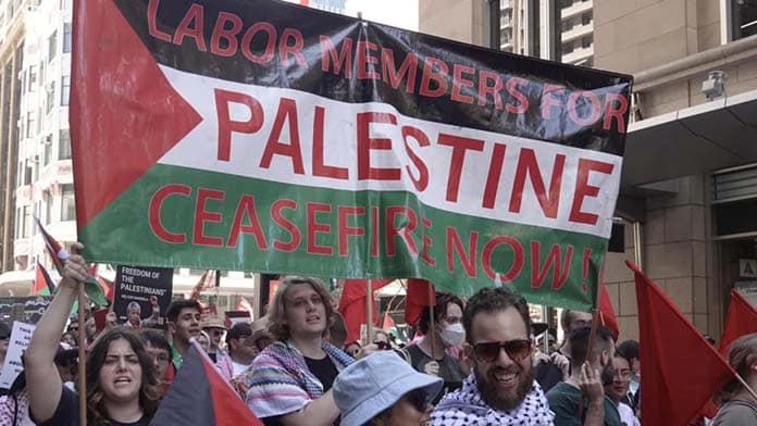 A group of protesters carry a banner that says "Labor Members for Palestine, Ceasefire Now!" on a Palestinian flag background